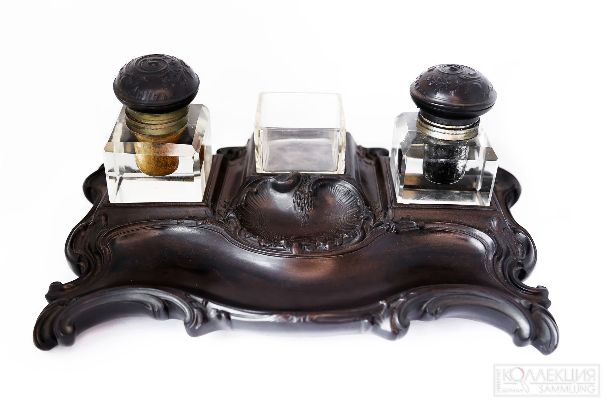Письменный прибор из двух чернильниц и подставки для перьев, изготовленный во Франции в 1870-х годах, интересен тем, что основание прибора и крышки чернильниц сделаны из первого натурального пластика Bois Durci (буа дюрси)